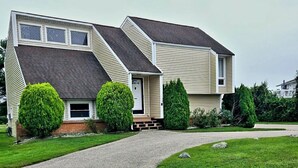 A two-story house with a front porch, a driveway, and well-maintained landscaping. - Returning to the summer rental market fully renovated 4 Br/2 bath home A/C (Narragansett)
