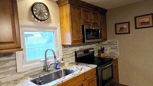 A kitchen with wooden cabinets, a stainless steel sink, a microwave, and an oven. - Returning to the summer rental market fully renovated 4 Br/2 bath home A/C (Narragansett)