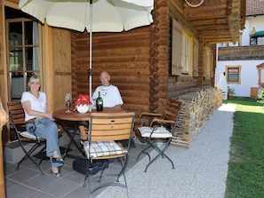 A wooden log cabin with a patio area featuring a round table, chairs, and a large umbrella. - Cabin in Seefeld Near Ski Slopes & Mountains (Seefeld in Tirol)