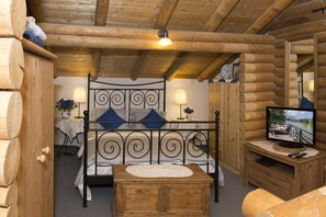 A log cabin room with a bed, bedside table, lamp, and a television on a wooden stand. - Cabin in Seefeld Near Ski Slopes & Mountains (Seefeld in Tirol)