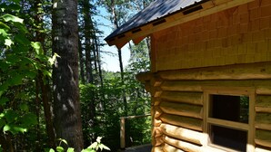 A log cabin with a wooden deck and a window.