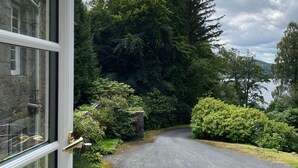 Une allée pavée mène à un bâtiment en pierre doté d’une fenêtre.