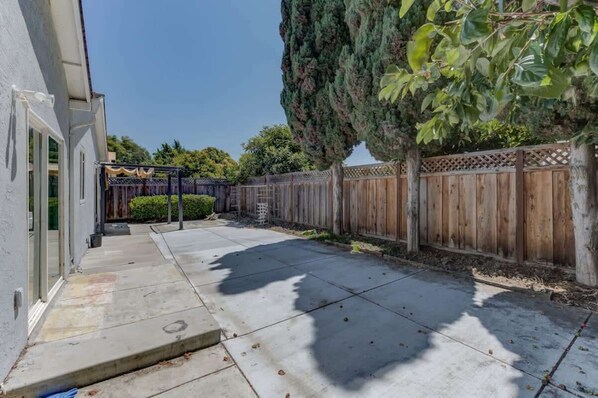 A backyard with a wooden fence, a tree, and a patio area. - @ Marbella Lane - Boho 'n Sleek Rtreat Pool Tble (Union City)