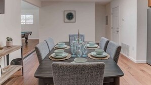 Een eetkamer met een rechthoekige tafel voor zes personen, omringd door grijze gestoffeerde stoelen.