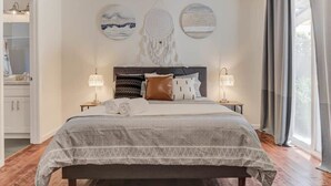 Een slaapkamer met een bed, nachtlampjes, een hoofdeinde en wanddecoratie.