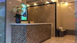 A reception desk with a digital screen, a vase of flowers, and a patterned wall. - Man'ai Hotel (Shanghai)