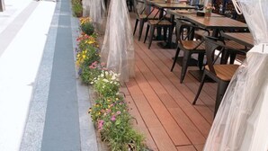 An outdoor seating area with wooden tables and chairs, covered with plastic sheets. - Man'ai Hotel (Shanghai)