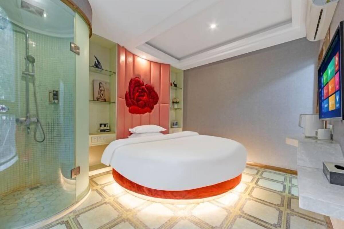A bedroom with a bed, a shower, and a large red flower decoration.