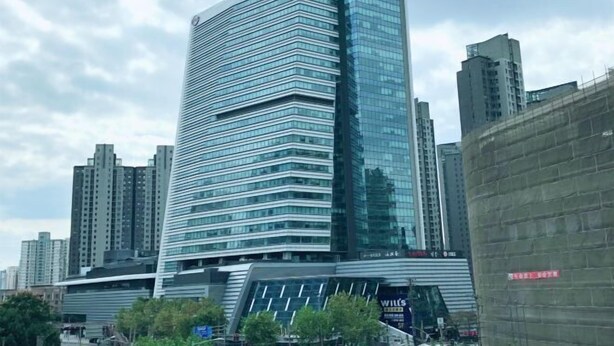 A modern high-rise hotel with a glass facade, surrounded by other buildings. - Man'ai Hotel (Shanghai)