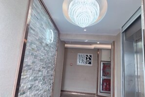 Un pasillo con pared de piedra, una araña y una puerta con panel de vidrio.