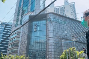 A modern building with a glass facade, surrounded by other high-rise structures. - Man'ai Hotel (Shanghai)