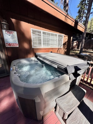 A hot tub with a wooden deck, a window with blinds, and a sign prohibiting diving. - Charming 4-bedroom house in delightful South Lake Tahoe near Tahoe golf course (South Lake Tahoe)