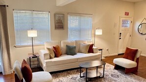 A living room with a white sofa, two armchairs, a coffee table, and a patterned rug.