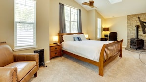A bedroom with a large bed, a leather chair, a heater, a stone wall, and a fireplace.