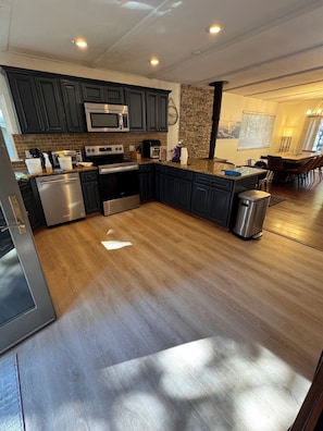A modern kitchen with dark cabinets, stainless steel appliances, a granite countertop, and a wooden floor. - Charming 4-bedroom house in delightful South Lake Tahoe near Tahoe golf course (South Lake Tahoe)