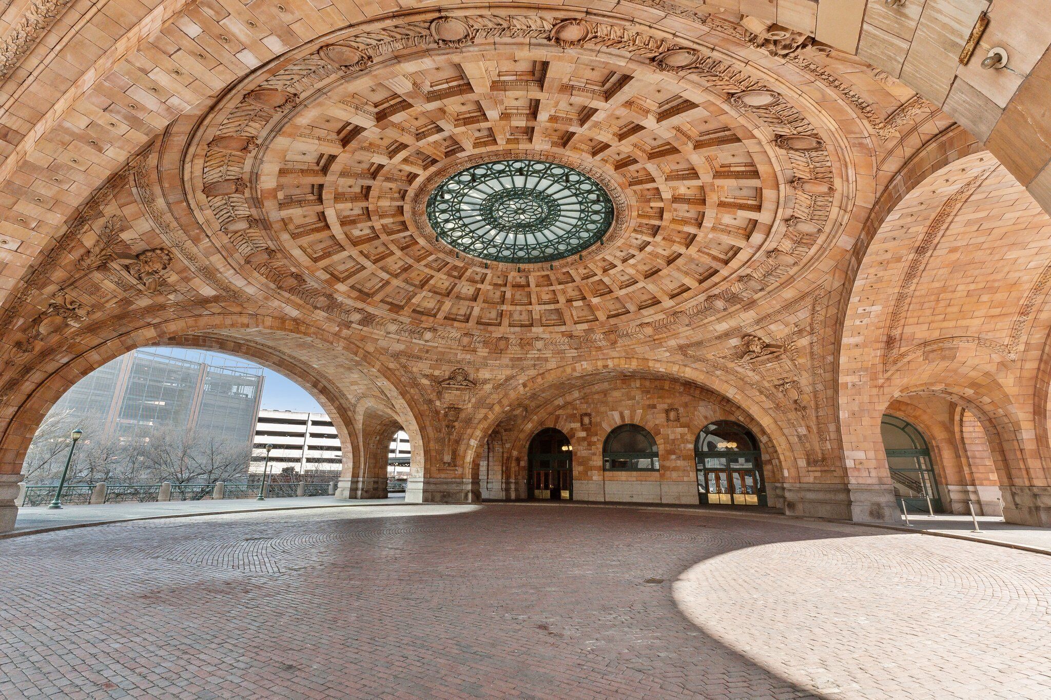 An arched architectural structure with a central circular window and brick flooring.