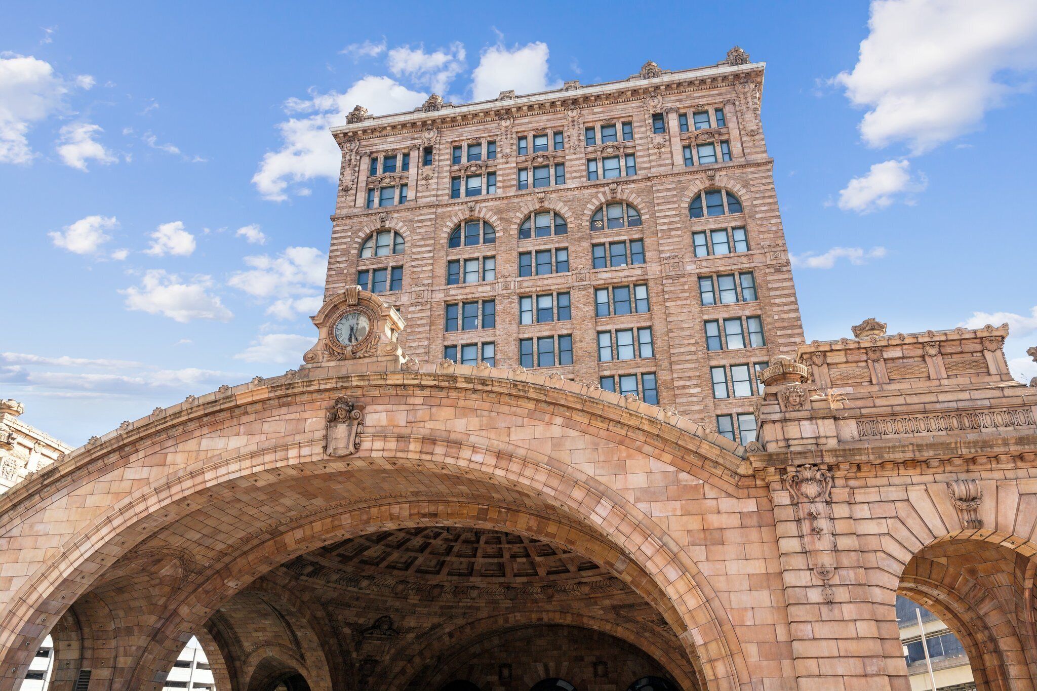 Uma ponte de pedra com arcos e um edifício grande com várias janelas ao fundo.