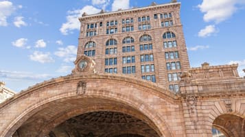 A stone bridge with arches and a large building with multiple windows in the background.