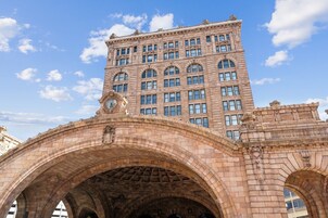 A stone bridge with arches and a large building with multiple windows in the background.