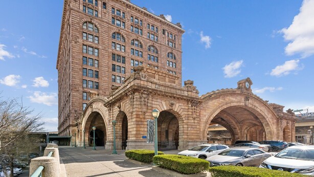 A historic building with a large arched entrance, multiple windows, and a clock tower.