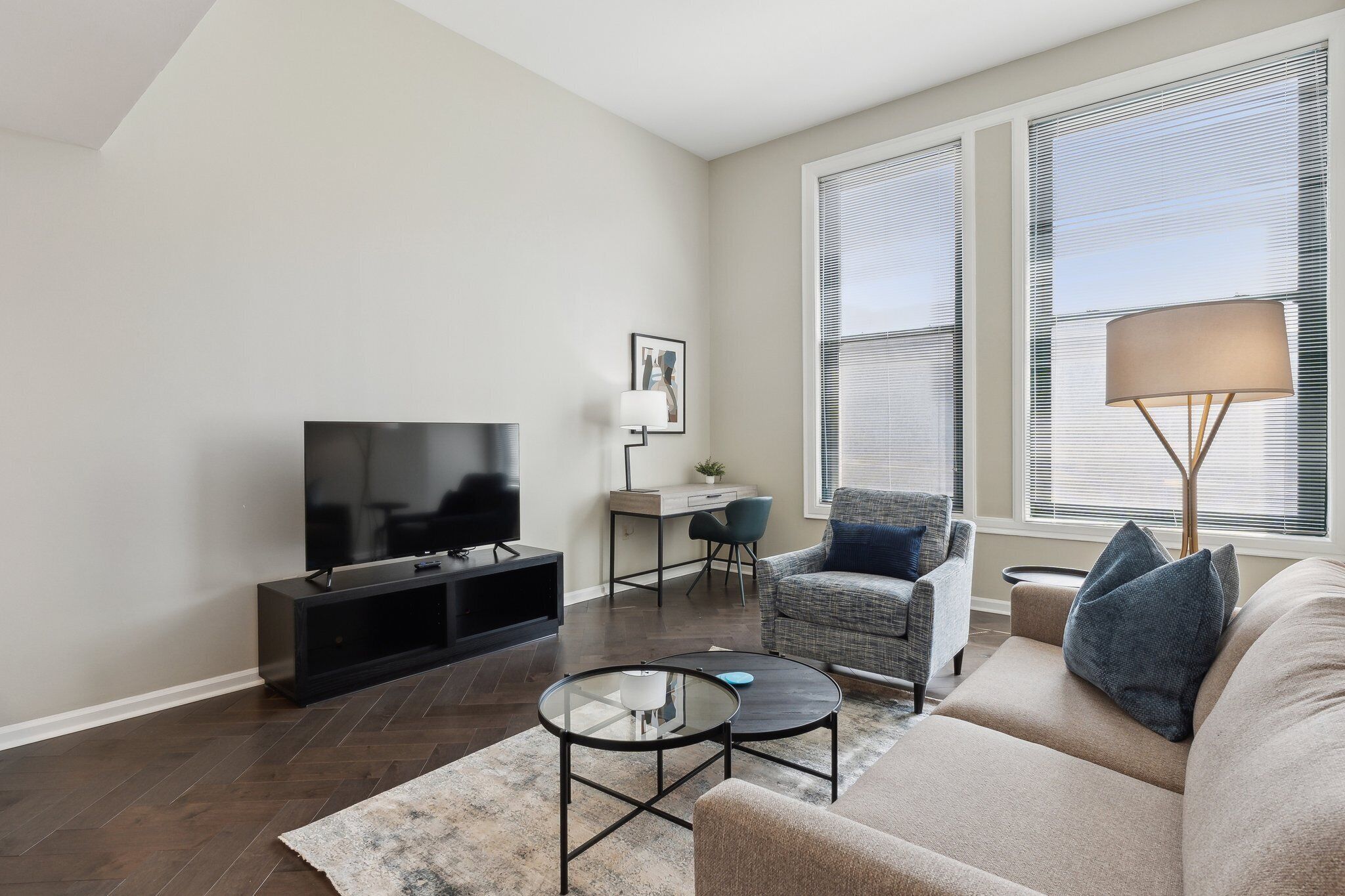 A modern living room with a flat-screen TV, a sofa, a coffee table, and a chair.