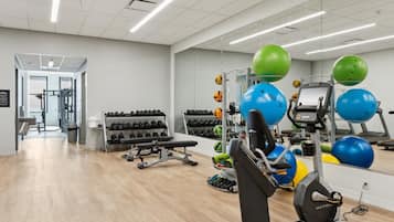 A gym with exercise equipment, weight racks, and a mirrored wall.