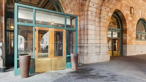 A building entrance with a glass door, a large planter, and stone arches.