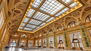 A grand hall with high ceilings, large windows, and ornate architectural details.