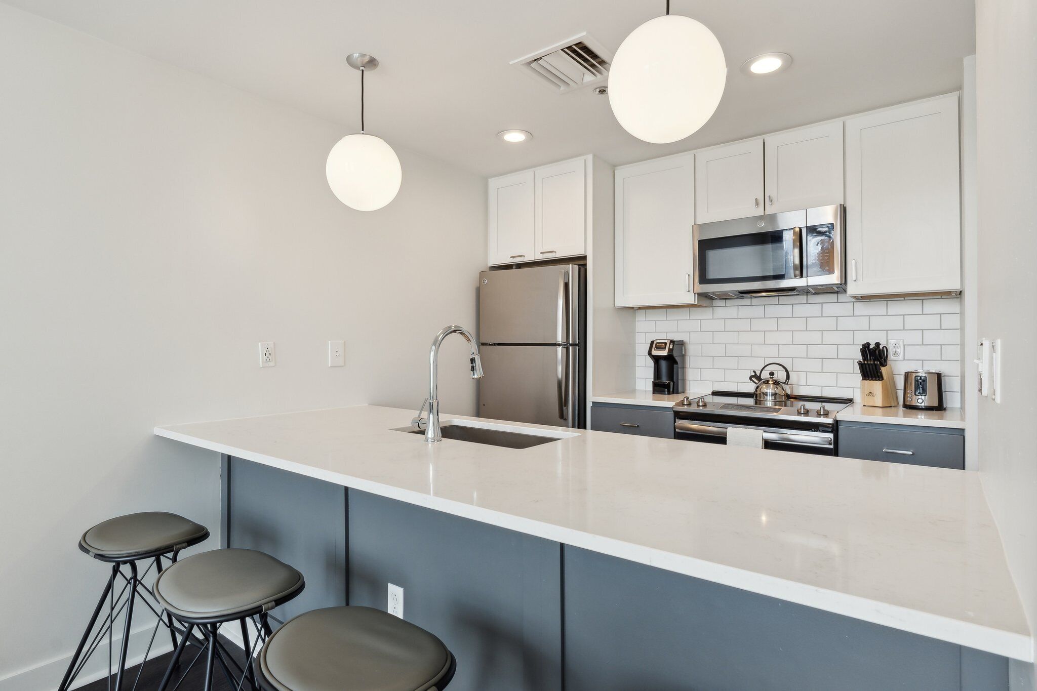 A modern kitchen with a large island, stainless steel appliances, and bar stools.
