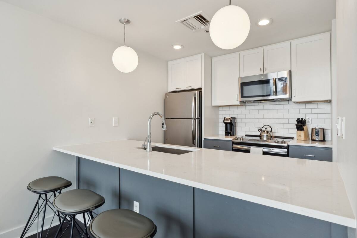 Una cocina moderna con una isla grande, electrodomésticos de acero inoxidable y taburetes de bar.