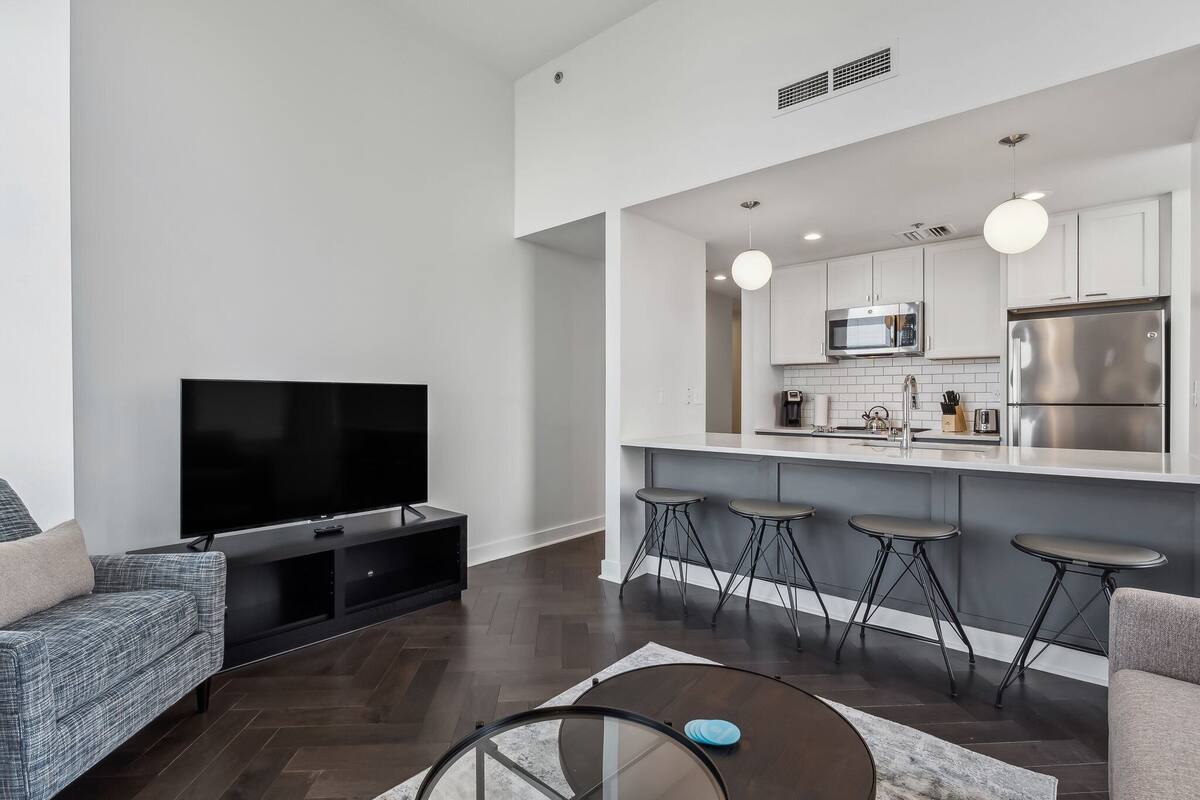Una sala de estar moderna con un televisor de pantalla plana, un sofá y una mesa de centro.