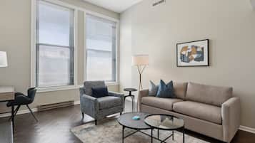 Un salon comprenant un canapé, un fauteuil, une table basse et une lampe.