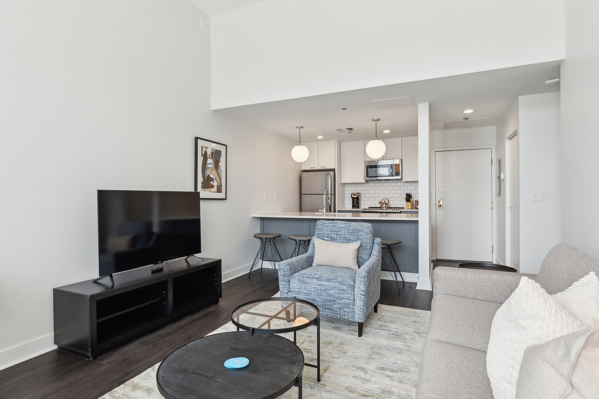 Una sala de estar moderna con una televisión de pantalla plana, un sofá, una mesa de centro y un comedor con una cocina al fondo.