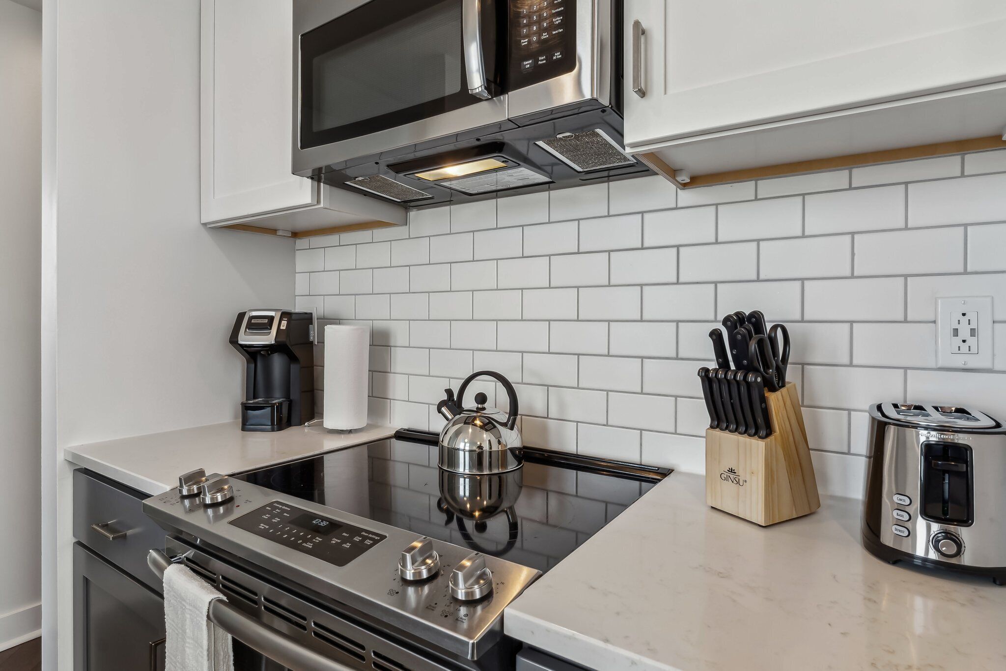 A modern kitchen with stainless steel appliances, a kettle, a coffee maker, and a knife block.
