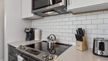 A modern kitchen with stainless steel appliances, a kettle, a coffee maker, and a knife block.