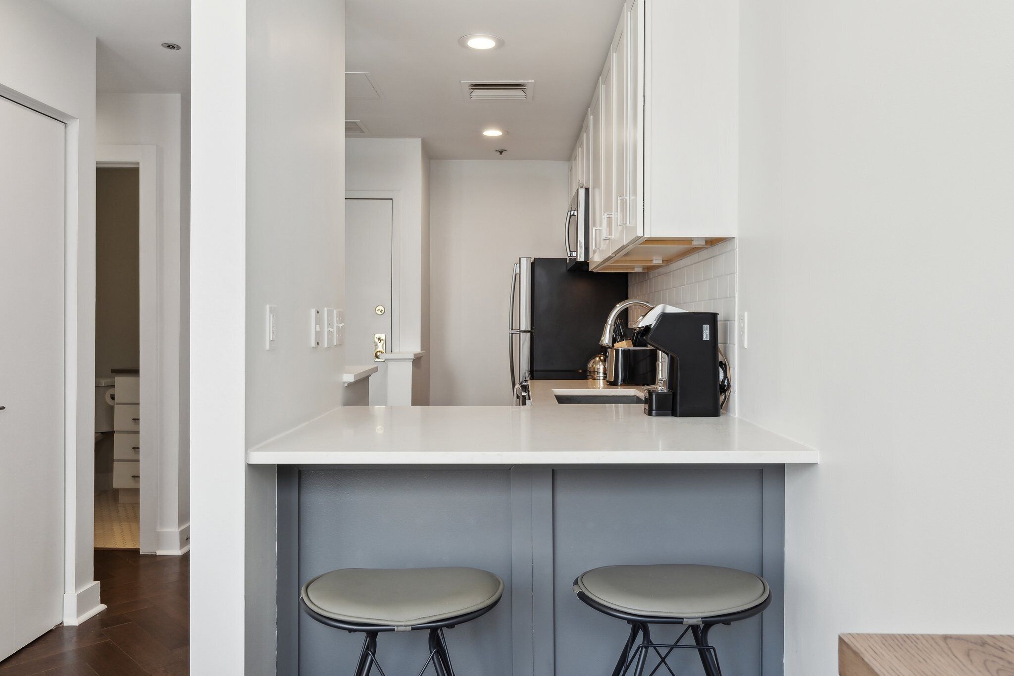 Una cocina moderna con armarios blancos, un refrigerador negro y una encimera blanca.