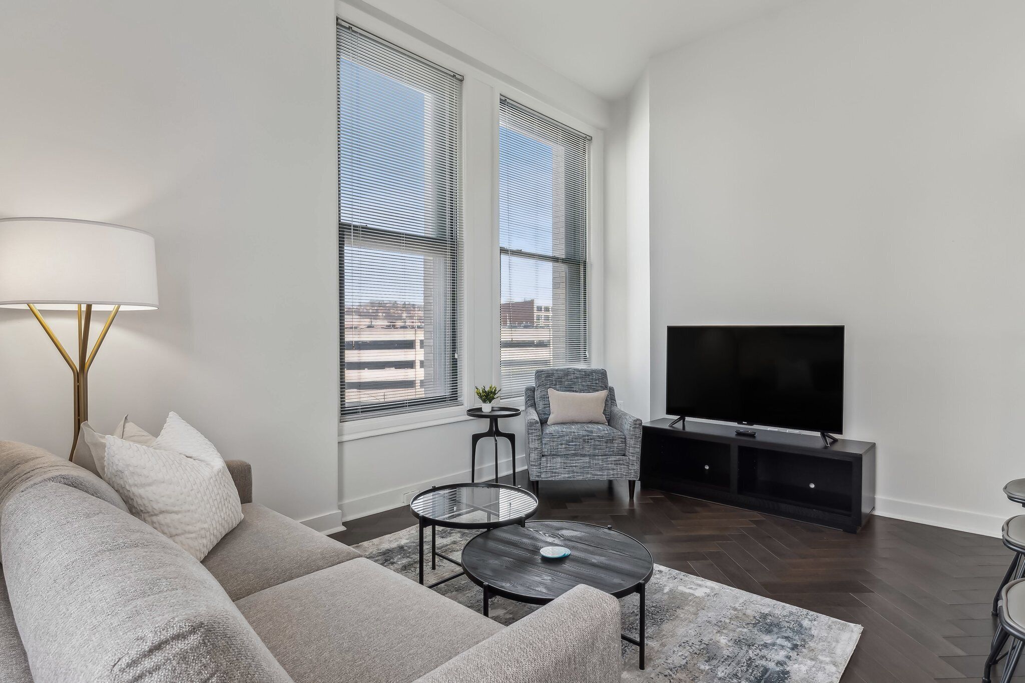 A modern living room with a sofa, two coffee tables, a TV, and a chair.