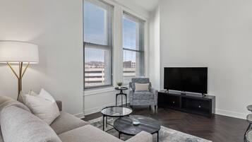 A modern living room with a sofa, two coffee tables, a TV, and a chair.