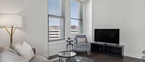 A modern living room with a sofa, two coffee tables, a TV, and a chair.