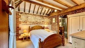 Un dormitorio con una cama de madera, una pared de ladrillo y un arco de piedra.