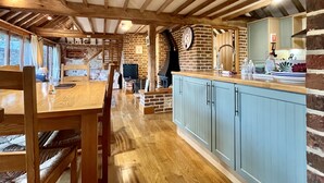 Una cocina rústica con vigas de madera a la vista, una chimenea de piedra y un armario azul.