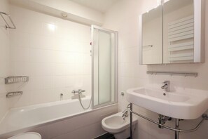Et moderne badeværelse med badekar, separat brusebad, toiletbidét og håndvask.