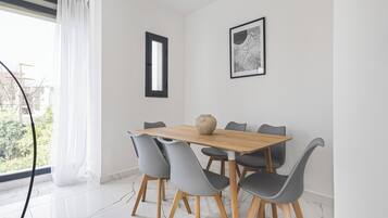 Un comedor con mesa de madera y sillas grises, un jarrón sobre la mesa y una obra de arte enmarcada en la pared.