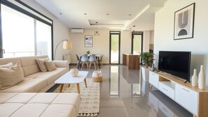 A modern living room with a sofa, coffee table, TV, and dining area. - Appartement de 3 pieces a Birkhadem (Algiers)