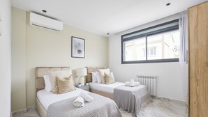 A hotel room with two beds, a window with a view, an air conditioner, and a radiator. - Appartement de 3 pieces a Birkhadem (Algiers)