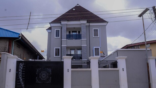 A multi-story residential building with a gated entrance, a balcony, and a staircase leading to the entrance. - Bamgbose Apartments - Sleeps 2 - Parking - Wifi (Lagos)