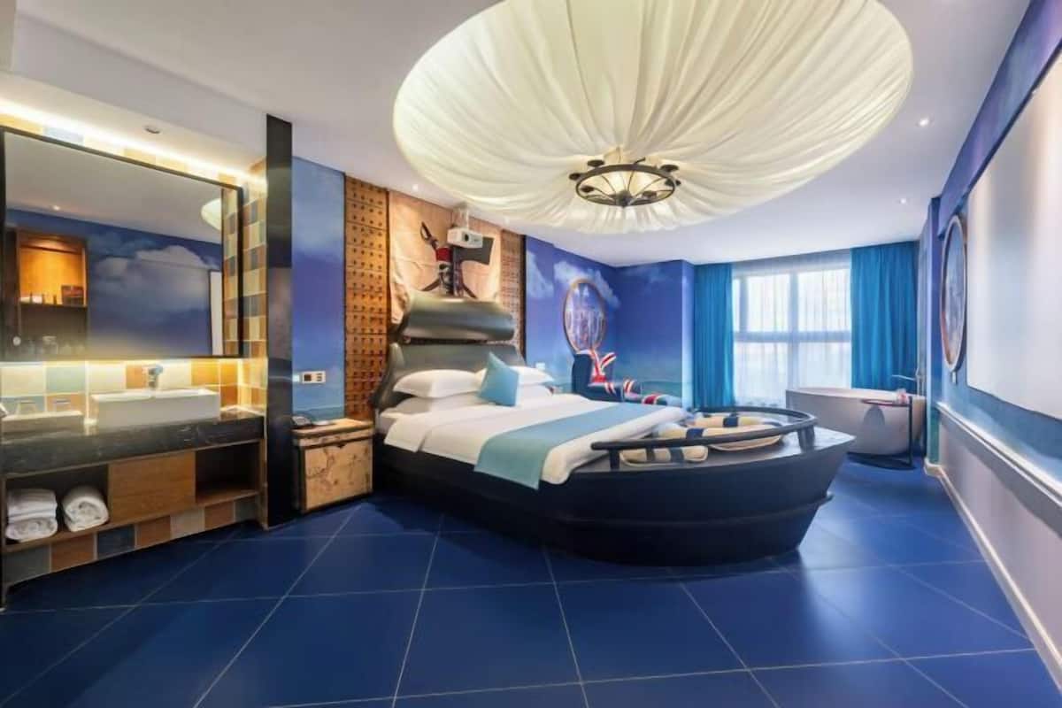 Ein modernes Schlafzimmer mit einem bogenförmigen Bett, einem großen Spiegel, einer Badewanne und einer Deckenleuchte.