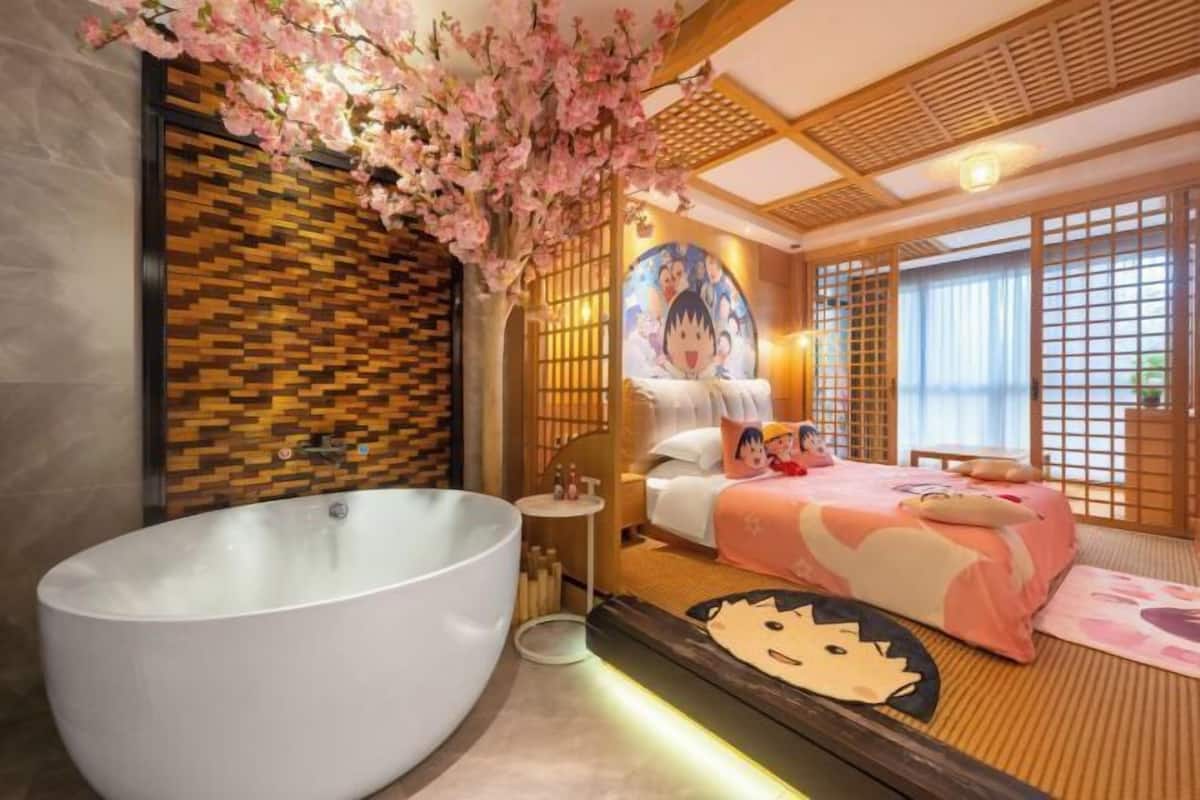 Ein Zimmer mit einer großen Badewanne, einem Bett mit einer Bettdecke im Comic-Stil und einer Wand mit einem Mosaikmuster.
