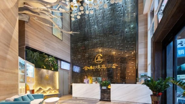 A hotel reception area with a modern design, featuring a reception desk, seating area, and a large glass wall with a decorative pattern. - KINCO Hotel (Huizhou Huiyang Station) (Huizhou)