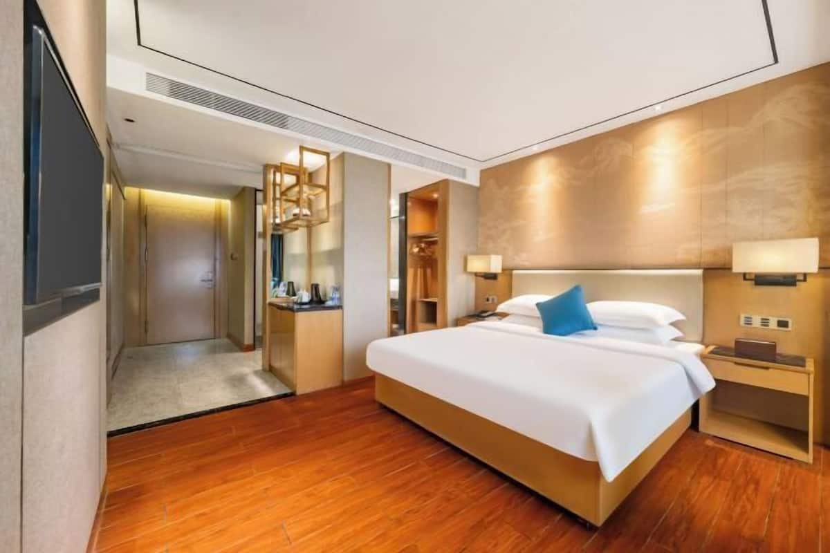 Ein Hotelzimmer mit einem großen Bett, Nachttischen, einem Schreibtisch und einem begehbaren Kleiderschrank.